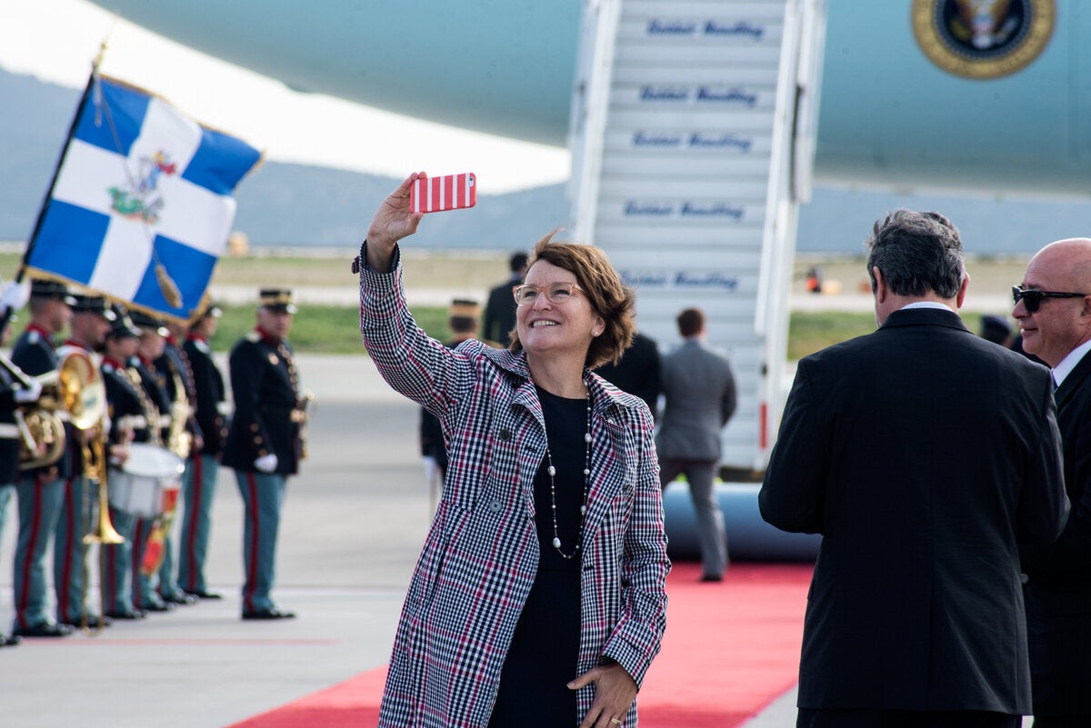 Η σύζυγος του Πρέσβη των Η.Π.Α Mary Pyatt βγάζει selfie. Στο βάθος κάποιος προσπαθεί να στρώσει (ακόμα) το χαλί.